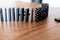 black domino cards with white dots in rows and balanced one after the other on a wooden table. Tiles of the domino before falling