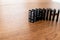 black domino cards with white dots in rows and balanced one after the other on a wooden table. Tiles of the domino before falling