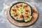 Black dough Pizza with ham slices, cherry tomatoes and Feta cheese pieces served on wooden plate served with culinary flour and sp