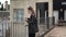 Black-dressed caucasian female with a suitcase standing in a hotel balcony admiring the view