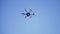 Black drone flying against the blue sky with spinning blades, bottom view. Clip. Compact quadcopter controlled by