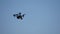 Black drone quadcopter with camera flying over blue sky. Black drone in the sky. Flying quadrocopter drone in the sky