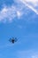 Black drone in the sky. Bright picture of quadcopter flying and