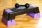 Black dumbbell lies on the step-platform for fitness. Feet on th