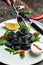 Black dumplings or pelmeni, ravioli with fish stuffing and caviar. Food recipe background. Close up