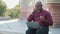 Black Elder man taking off glasses massaging nose bridge feels unhealthy reduce eye strain after long laptop usage