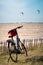 Black Electric bike with a red basket parked in grass against seaside with many kitesurfers