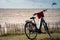 Black Electric bike with a red basket parked in grass against seaside with many kitesurfers