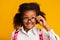 Black Elementary Schoolgirl Looking Over Glasses At Camera, Studio Shot