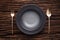 Black empty bowl fork spoon on wooden table background