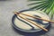 Black Empty Plate with Brown Bamboo Chopsticks Palm Tree Leaf on Dark Grey Concrete Stone Background. Asian Thai Chinese Cuisine