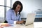 Black ethnicity woman sitting at computer laptop desk typing concentrated working