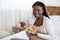 Black Expectant Woman Eating Fresh Vegetable Salad, Sitting On Bed At Home