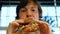 Black eyed guy eats tasty hamburger against blurry windows