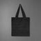 Black fabric bag on dark background. Canvas handbag hanging on cement wall