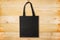 Black fabric bag on wooden background. Reusable black tote bag on wooden texture