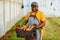 Black farmer holding crate full of vegetables in greenhouse, smiling