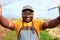 Black farmer taking a selfie, smiling, with greenhouse in background