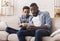 Black father and son looking at smartphone screen with shocked face