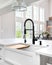 A black faucet on a white farmhouse sink.