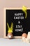 Black felt letter board with slogan - Happy Easter and Stay at Home on beige background. Vertical orientation