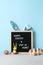 Black felt letter board with slogan - Happy Easter and Stay at Home on pastel cyan background. Vertical orientation