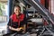 A black female automotive mechanical worker checks EV car at a fixing garage.