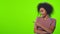 Black female has broad smile indicates aside at blank space over chroma key