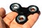 Black fidget spinner toys held in palm of adult male person, white background