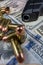 Black firearm and bullets  close-up on a pile of United States currency against a black background.