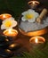 Black flat stones for hot massage against the background of burning candles and sets for SPA procedures