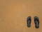 Black Flip Flops on smooth sand background at the beach