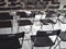 Black folding chairs stand in the white conference room