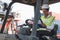 Black foreman woman worker driving forklift checking at Container cargo harbor to loading containers and has a problem. African