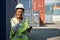 Black foreman woman worker working checking at Container cargo harbor holding laptop computer and walkie-talkie to loading