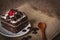 Black Forest Cake topping cherry putting on the white plate on the sack and wood background there are wood spoon and Chocolate
