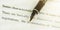 Black fountain pen with golden quill on document text macro