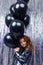 Black Friday. Attractive young stylish caucasian girl stands with black helium balloons on a shiny holiday background