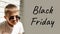 Black friday concept banner. A boy in sunglasses sits leaning against a brick wall and grimaces