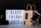 Black friday Sale words on lightbox with black price tag and gifts front view on dark background