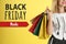 Black Friday Sale. Young woman with shopping bags on yellow background, closeup