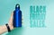 Black Friday sales text near female hand holding aluminum thermo water bottle of blue. Background of cyan, Aqua menthe color.