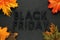 Black Friday text with autumn leaves on black slate