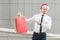 Black friday in winter. Happiness red head businessman in santa hat , holding shopping bags on hands, pointing fingers and looking