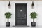 Black front door of white house with trees