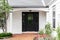 A black front door of a white ranch farmhouse.