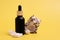 Black frosted glass bottle with a pipette with shells on an isolated yellow background.