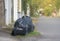 Black garbage bags on dirty ground at side road beside the house waiting for the rubbish keeper officers to take away