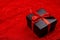 Black gift box with red ribbons on a red lace background