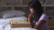 Black girl praying with Bible on bed